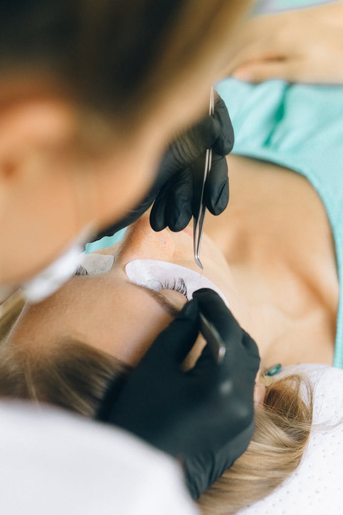 A beautician applies eyelash extensions to a clients lashes in a beauty salon.