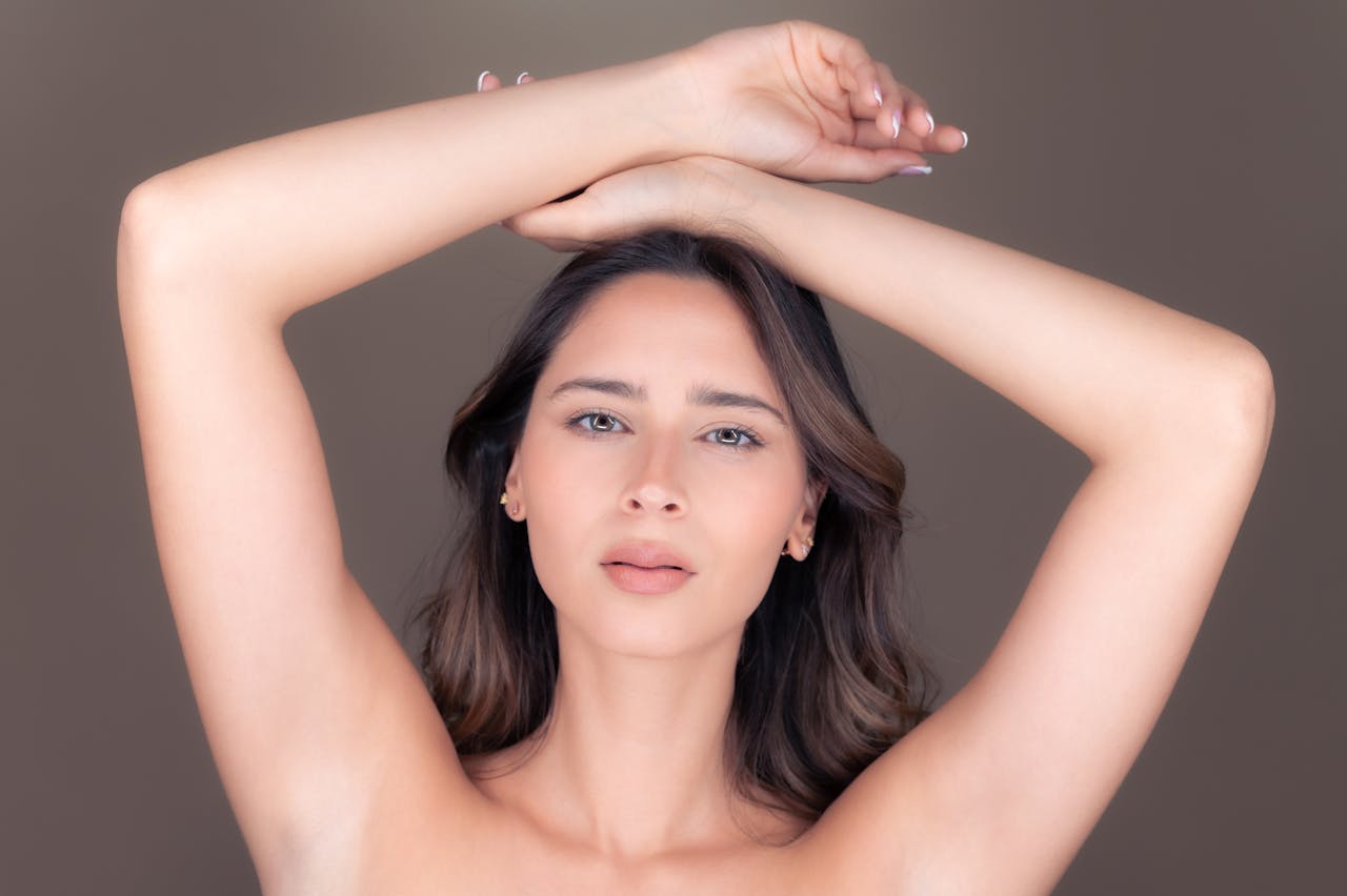 A graceful portrait of a beautiful brunette woman posing with arms raised in a studio setting.